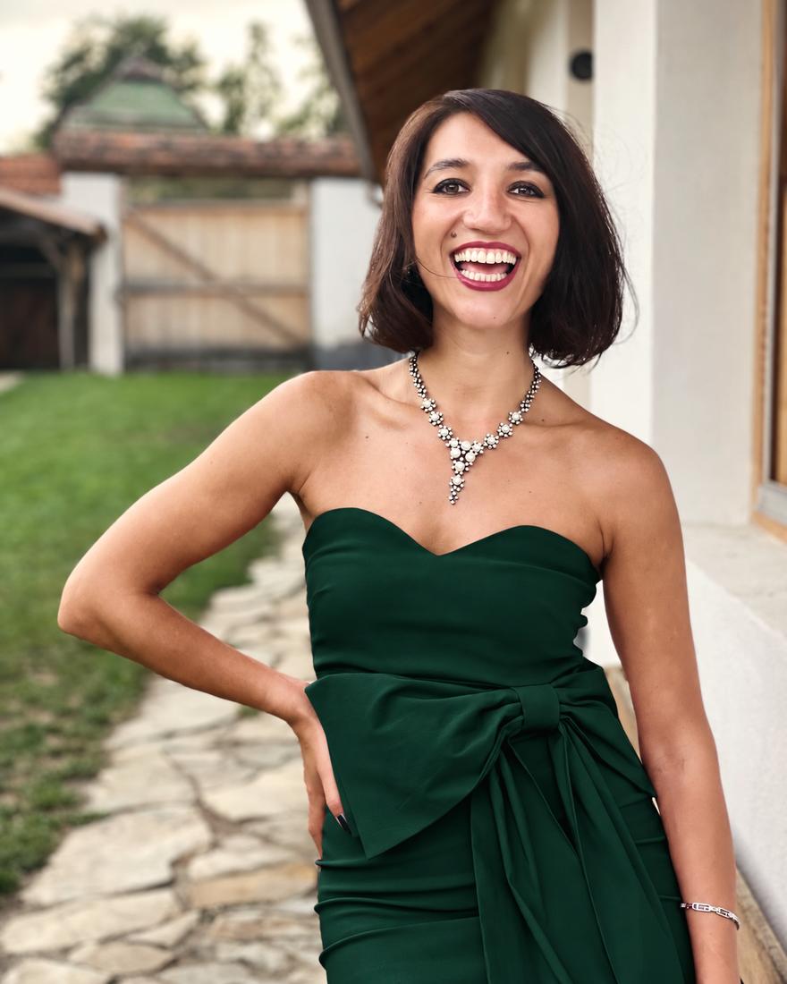Irina laughing in a forest green dress and pearl necklace