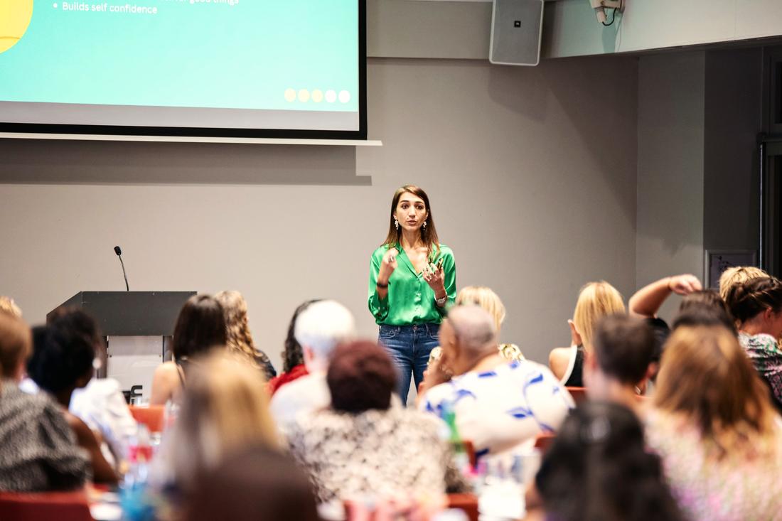 Irina speaking to a room full of women in a green satin shirt