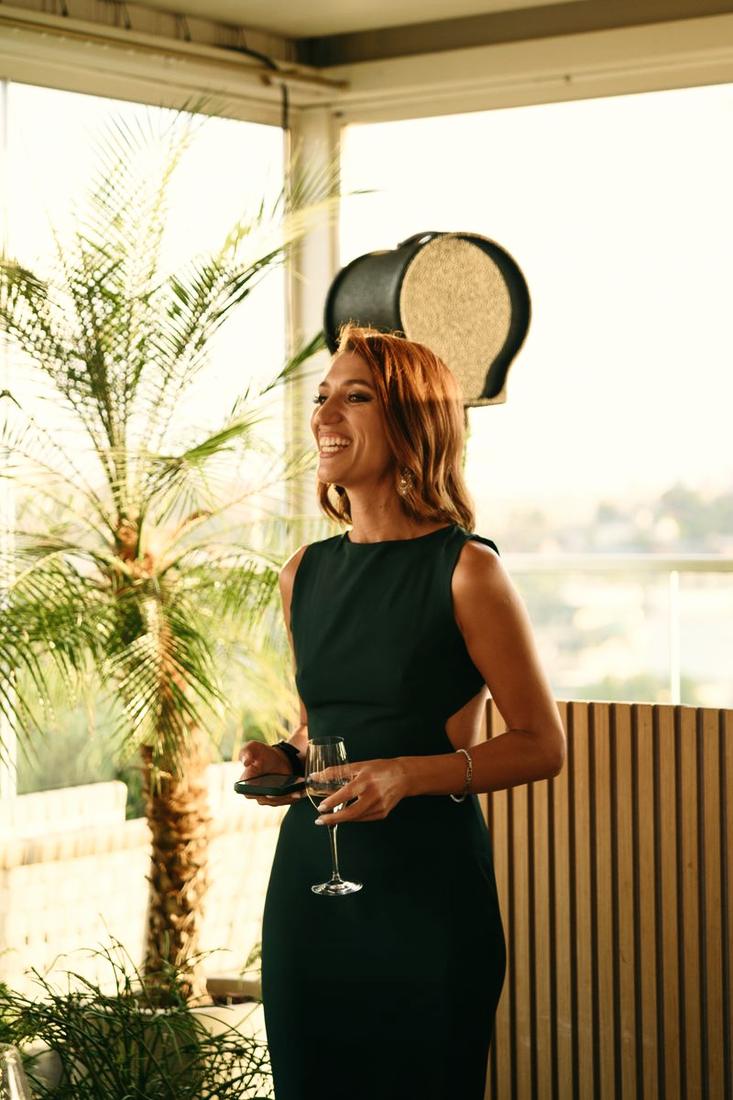 Irina laughing at an event, glass of Prosecco in hand