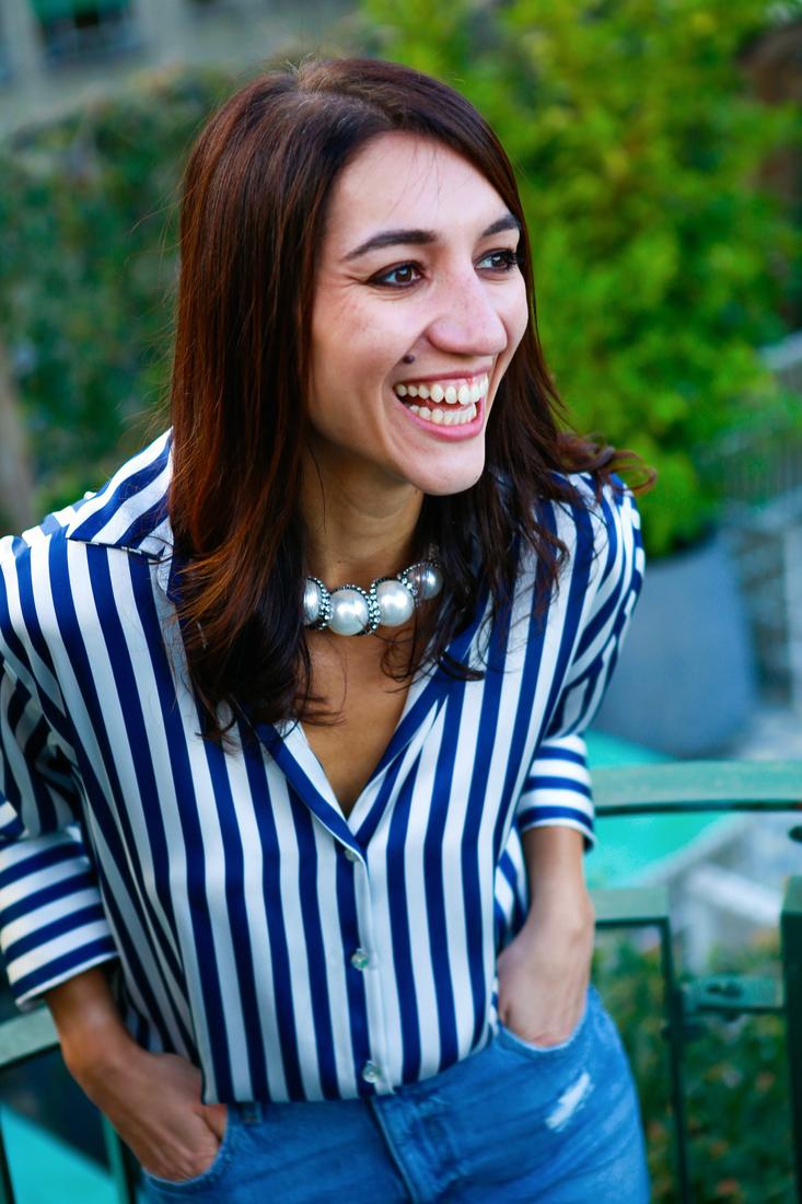 Irina laughing on a sunny balcony in a striped shirt