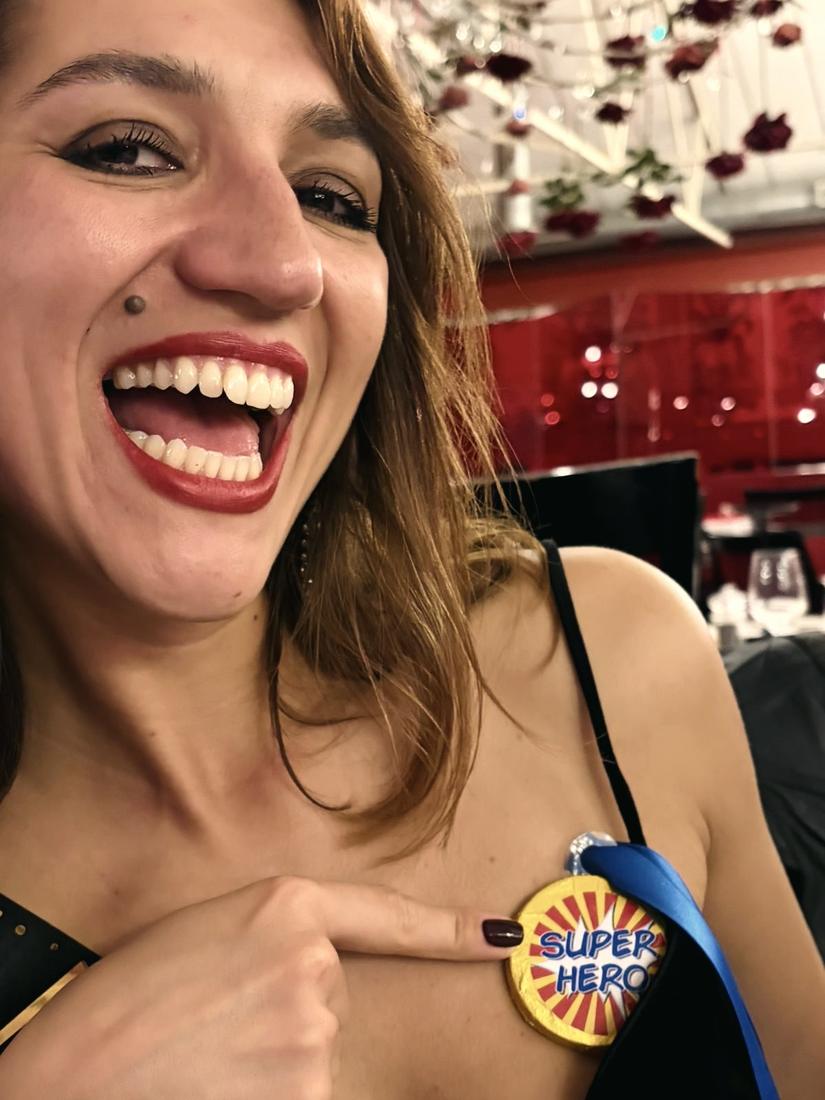 Irina laughing and pointing at a Super Hero badge