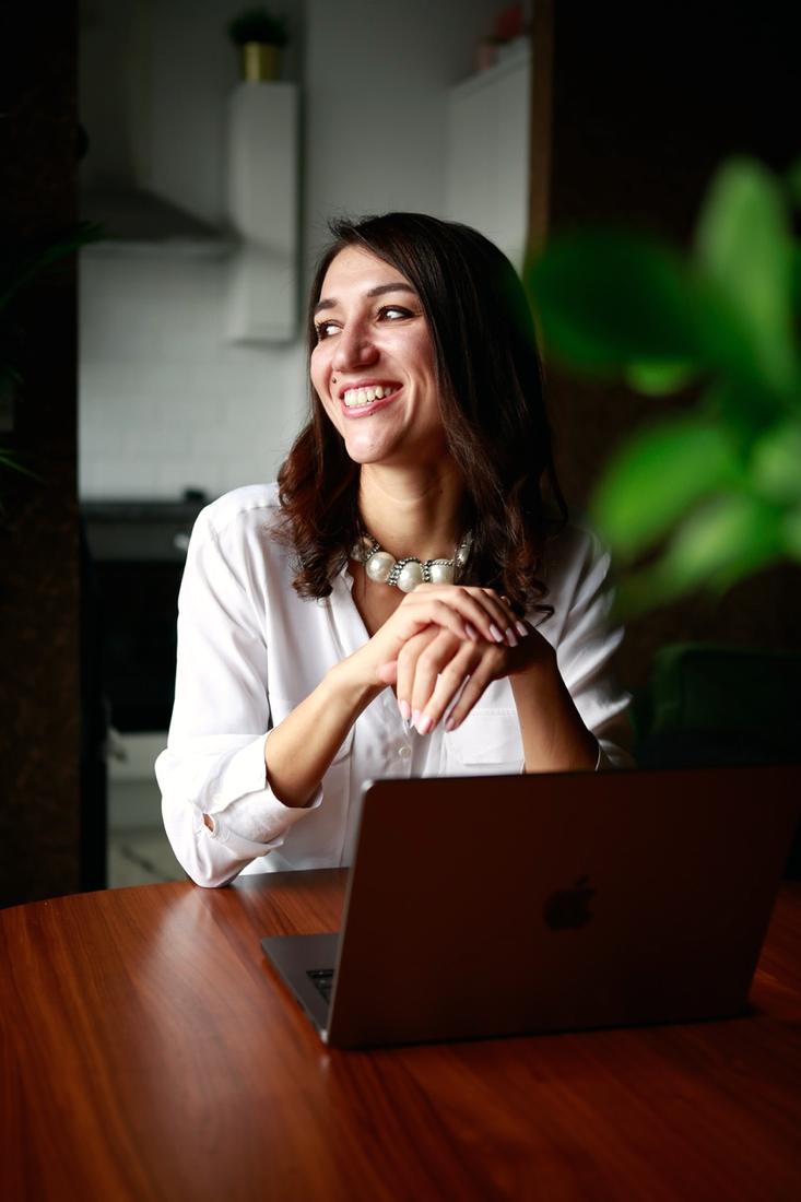 Irina smiling at a table with her laptop